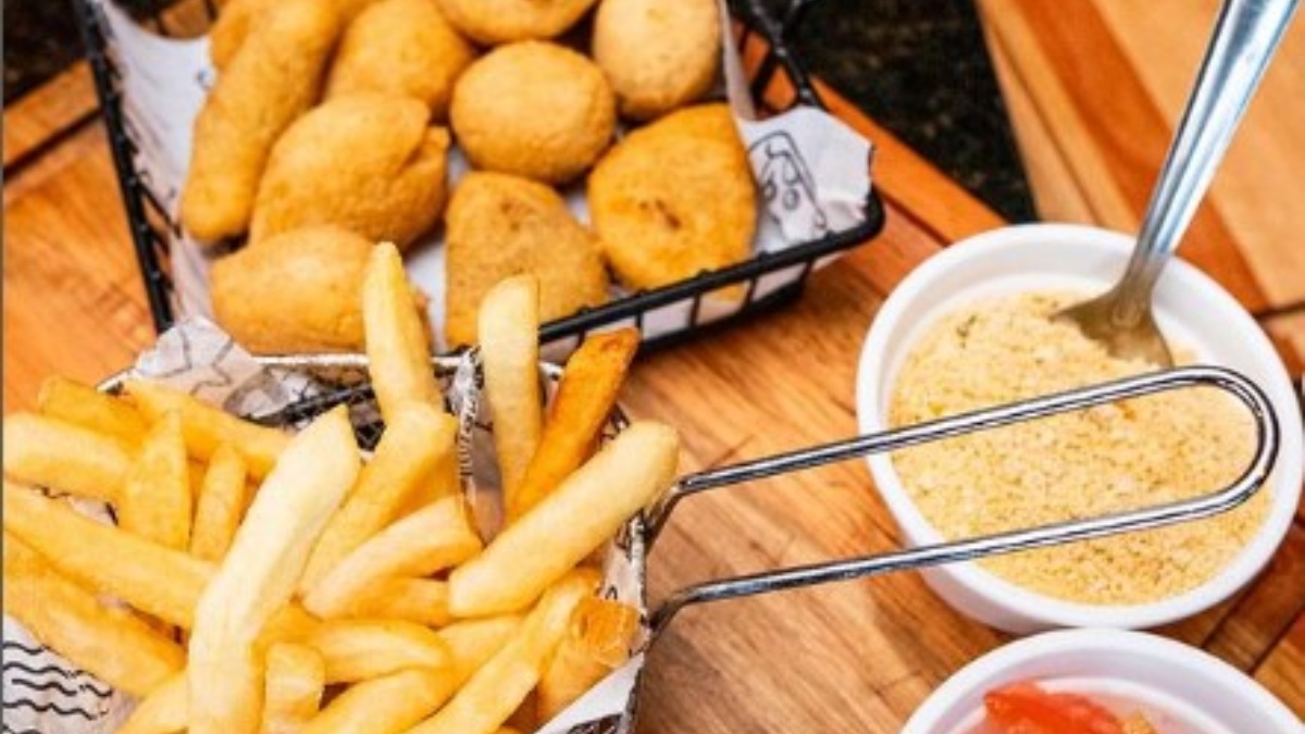 Farofa, vinagrete, arroz, bolinha de queijo, coxinha, risole de carne e de pizza, além de batata frita são servidos como acompanhamento. Foto: Reprodução/Redes sociais