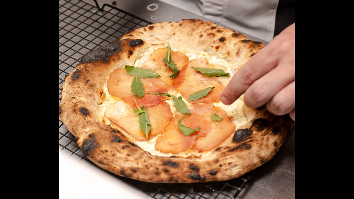 Pizza Salgada possui queijo pomerode vermont, mini speck, feta salto do panema, rúcula baby e mel de abelha Borá. /Foto: Divulgação