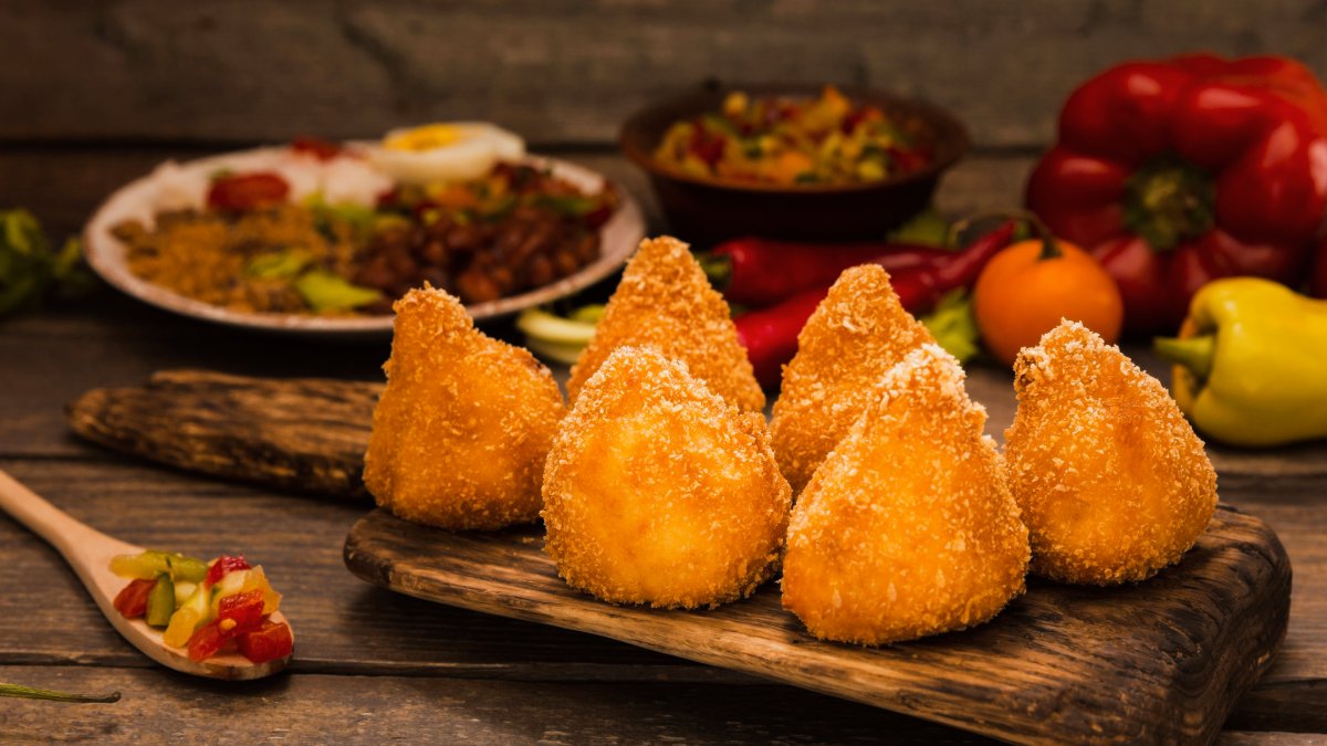 Você prefere começar pela ponta ou pela base? Bom, não importa como você come, muito menos qual tamanho, formato ou recheio prefere, a verdade é que a coxinha é o quitute mais popular e mais amado pelos brasileiros. Foto: Reprodução/Freepik