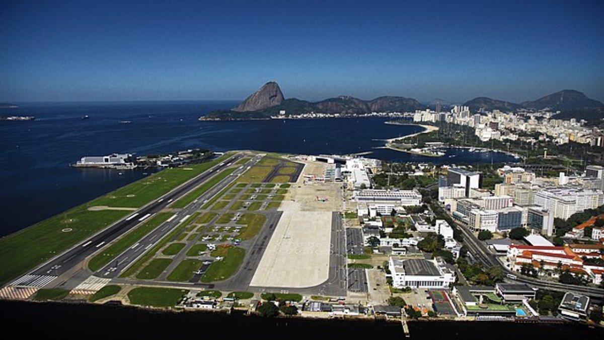 O Aeroporto Santos Dumont, no Rio de Janeiro, é amplamente reconhecido não só pela sua localização icônica, mas também pelos estímulos operacionais que impõe, apesar de disputar espaço com o Aeroporto de Galeão. Situado entre a Baía de Guanabara e as montanhas que cercam a cidade, o aeroporto é um dos mais movimentados do Brasil, mas sua geografia peculiar o coloca entre os mais desafiadores para pousos e decolagens. Nas classificações de aeroportos, o Santos Dumont é frequentemente mencionado como um dos mais críticos em termos de operação. Sua pista curta exige precisão absoluta dos pilotos. Qualquer erro de cálculo pode resultar em graves consequências, já que, de um lado, há o mar, e do outro, a área urbana densamente habitada do centro do Rio.