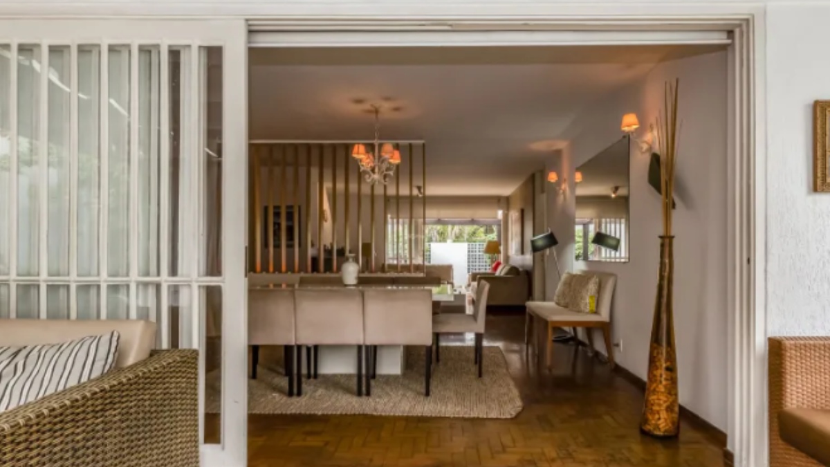 Sala de estar e de televisão da casa possui porta de correr que abre para o jardim.