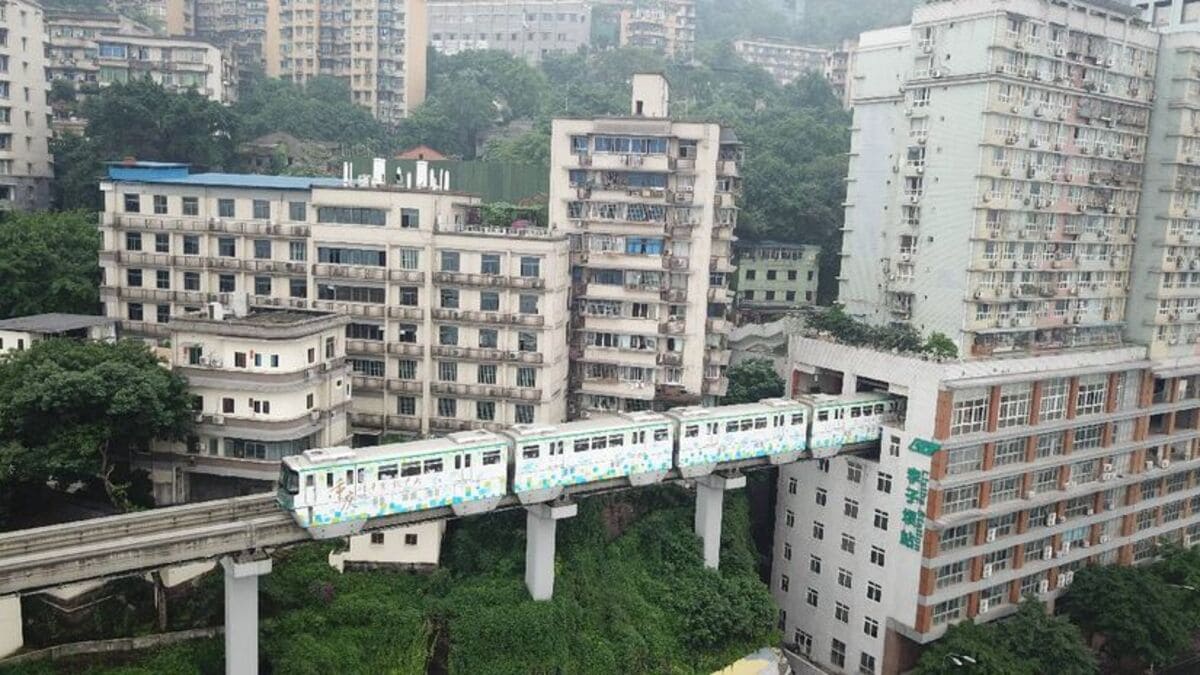 O trem atravessa os andares centrais do edifício residencial, revelando uma solução urbana criada para aproveitar o espaço em uma cidade densamente povoada.