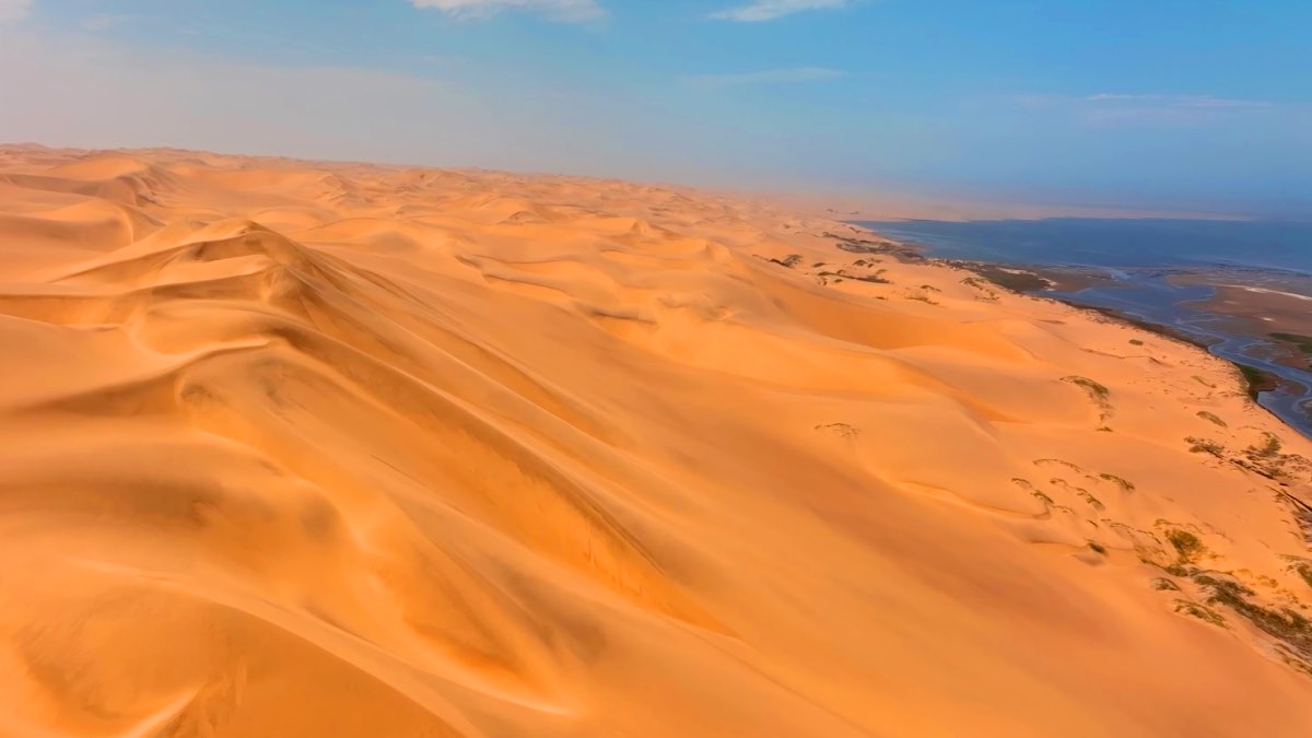 3. O Deserto do Namibe avança até o Atlântico e revela uma paisagem onde dunas e ondas dividem o mesmo horizonte.
