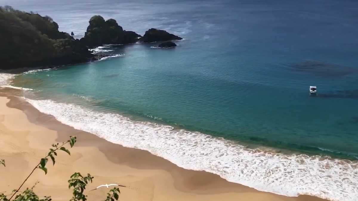 O acesso é uma aventura à parte: para chegar à areia, os visitantes precisam descer uma escadaria encravada em uma fenda estreita entre as rochas.