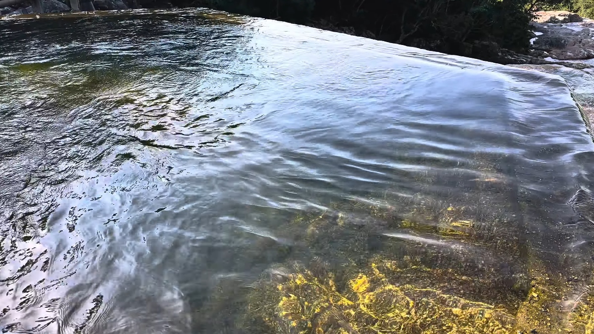 Do topo da queda d'água, a impressão é de que o rio se lança diretamente sobre o mar, criando uma borda infinita natural que transforma a paisagem em um cenário quase irreal.