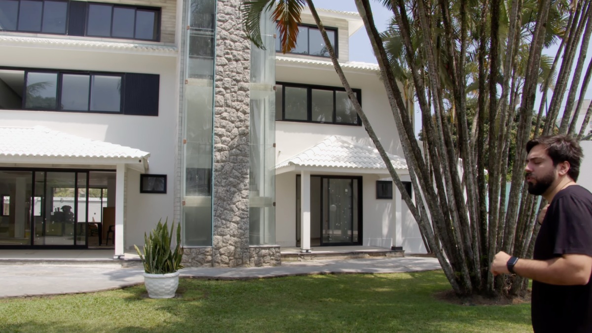 O projeto de interiores utiliza painéis ripados e portas mimetizadas para criar um ambiente sofisticado e visualmente limpo na área social. Foto: Reprodução/Youtube