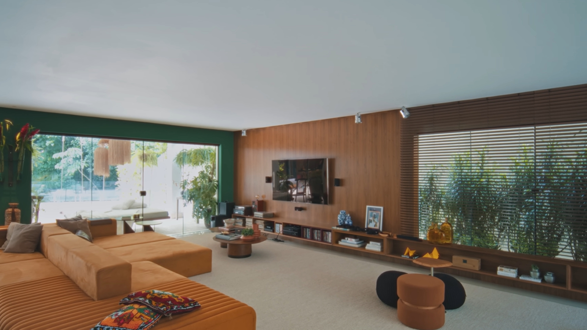 O living conta com poltronas Mars e mesas com base cimentícia, enquanto a área externa possui balanços de design assinado e uma piscina generosa integrada ao paisagismo nativo.