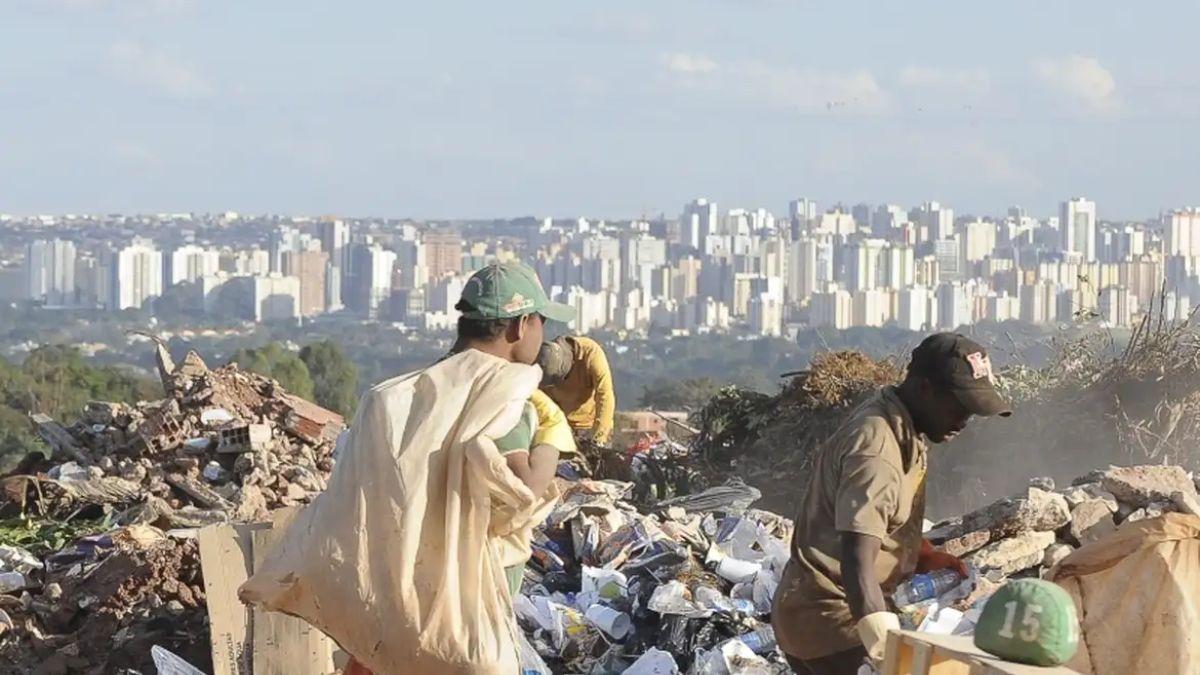 Catadores trabalham em meio ao descarte enquanto a silhueta moderna da capital, no horizonte, revela o contraste da desigualdade. Wilson Dias/Agência Brasil/Arquivo